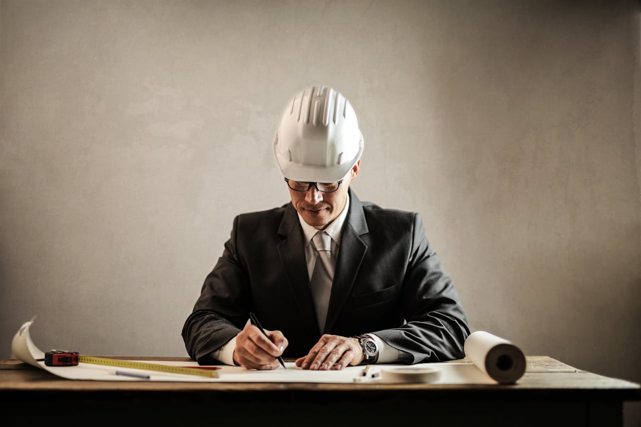 services-04 Engineer in a suit drafting architectural plans at a desk indoors.